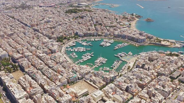 Beautiful aerial perspective of the dense urban cityscape of piraeus, featuring the iconic circular zea marina filled with luxurious yachts and boats on the stunning coast of attica, greece