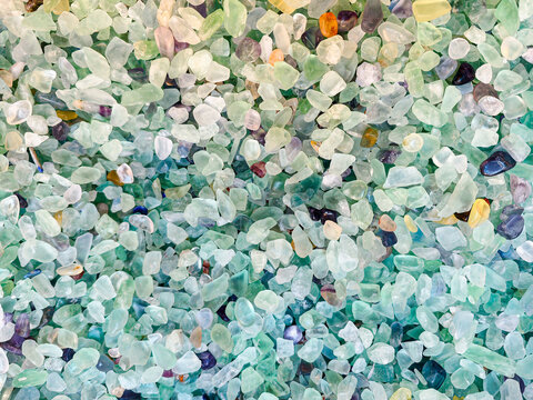 Green sea glass and fluorite pebble texture background. translucent pebbles show various shades of mint and teal for decorative landscaping use.