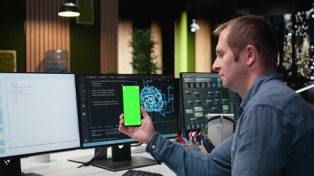 Green screen mockup smartphone used by IT specialist developing AI algorithms in high rise office. Admin taking break from debugging neural network models to use chroma key mobile phone.