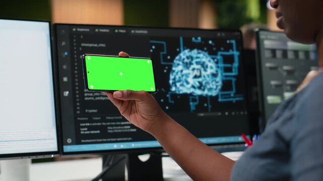 Green screen phone used by woman in company workplace doing tech quality assurance. Woman in office watches tutorial on programming languages with chroma key smartphone for coding workflows.