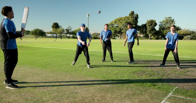 Male coach using bat, flicking ball, triggers team retrieving, tossing, and catching in slip drill