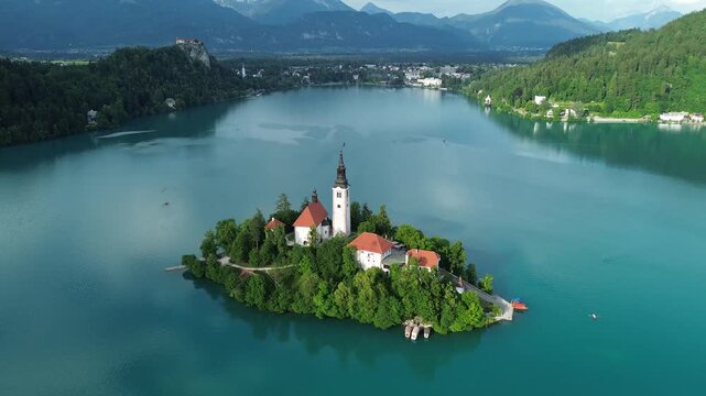 4K 30fps aerial view of Bled Island with the Assumption of Mary Church on Lake Bled, Slovenia. Beautiful cinematic footage of the iconic island surrounded by turquoise blue water and Alps mountains