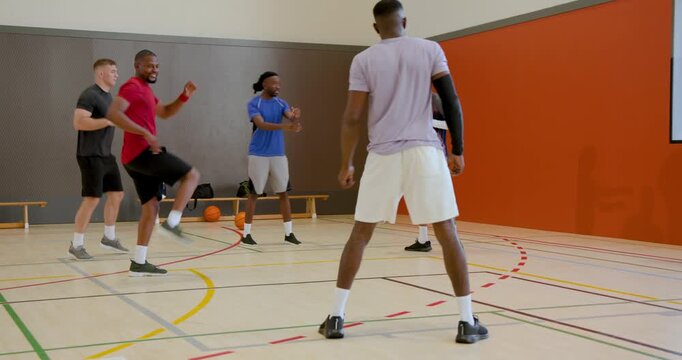 Diverse sports team practicing drills on basketball court in gear, with whistle and clipboard