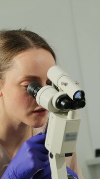 Gynecologist reviews cervical area through colposcope during checkup. Specialist keeps steady focus evaluating visible tissue changes