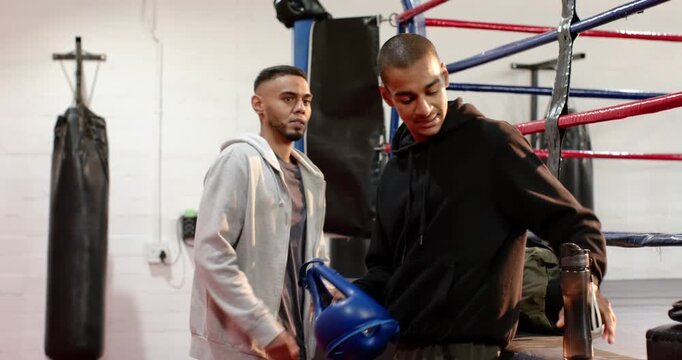 Male training partners walking to ring apron camo duffel taking gloves and water preparing sparring