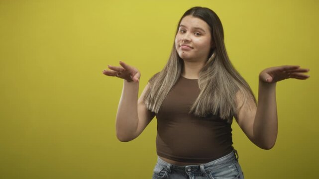 Young woman raises both hands in a palms up shrug with closed eyes and relaxed hands in a studio; indifference casual.