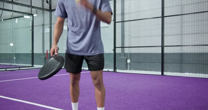 Diverse friends warming up on purple court and juggling ball on padel paddle
