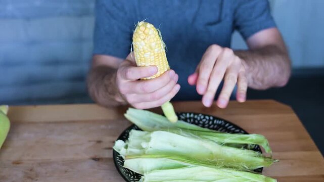 Man peeling fresh corn husk from cob during kitchen food video Full HD preparation