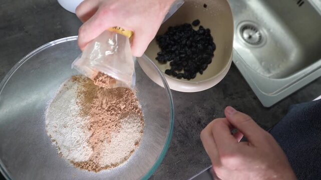 Adding dry ingredients into flour mixture with raisin for homemade baking video Full HD