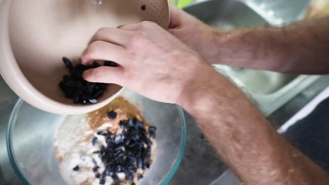 Adding soaked raisin into flour mixture during homemade baking process video Full HD