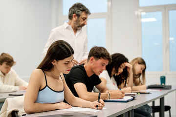 Fototapeta premium Students taking an exam with teacher supervising