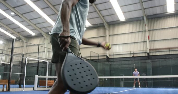 African american player dribbling ball tossing high swinging paddle serve as opponent bracing