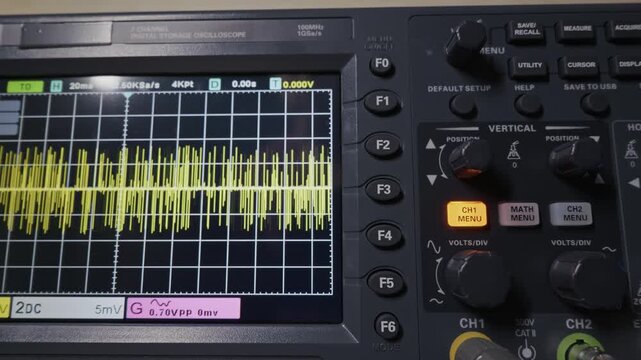 Digital oscilloscope screen displays a yellow signal waveform as the camera zooms out to reveal control knobs. Concept of electronic engineering, signal processing, and diagnostic testing.