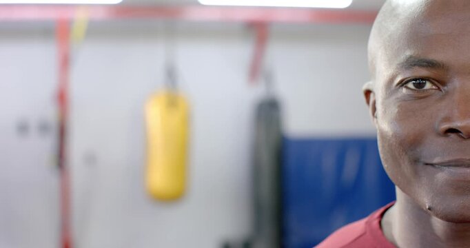 African American man holding focused gaze shifting to smile refocusing by punching bags, copy space