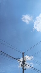 Fototapeta premium Electrical and Fiber Network Installation on Utility Pole Under White Clouds and Blue Sky, Modern Infrastructure and Connectivity Background