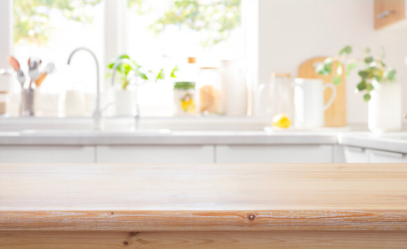 Mockup space on wooden table top with blurred modern kitchen counter as background