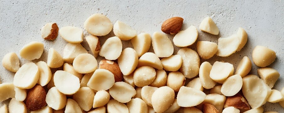 Panoramic flat lay of macadamia nuts creates an elegant, uniform pattern with a pale neutral palette. Soft natural lighting emphasizes the clean, minimalist aesthetic.