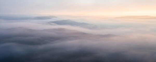 Obraz premium Aerial view of mountain peaks emerging from dense cloud cover
