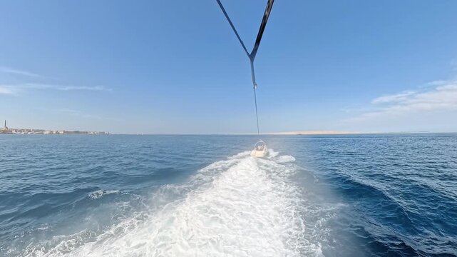 First person view of a parasailing flight over the deep blue sea on a sunny day