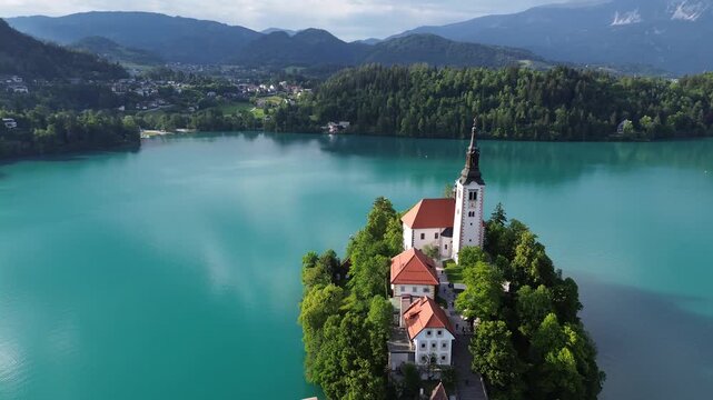 4K 30fps aerial view of Bled Island with the Assumption of Mary Church on Lake Bled, Slovenia. Beautiful cinematic footage of the iconic island surrounded by turquoise blue water and Alps mountains