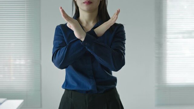 Business woman making an X sign with crossed arms and open hands, representing stop, rejection, prohibition, warning, policy violation and negative response concepts.