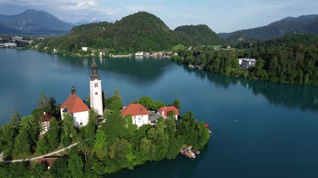 4K 30fps aerial view of Bled Island with the Assumption of Mary Church on Lake Bled, Slovenia. Beautiful cinematic footage of the iconic island surrounded by turquoise blue water and Alps mountains