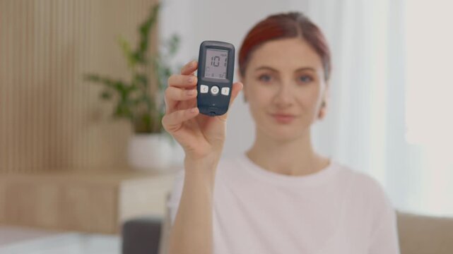 A woman holds a glucometer up to the camera displaying a reading of 101 mg dL. She discusses her glucose level and its importance for managing health.