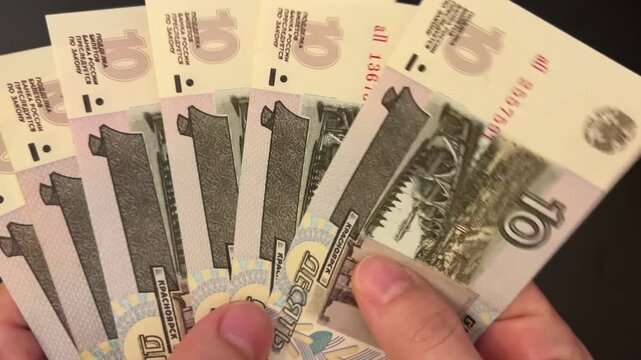 Counting rouble banknotes. Female hands count 10 russian roubles cash. Frugality, family budget, and savings concept