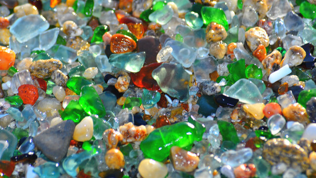 A beautiful backdrop of sea glass, mixed with small pebbles of various shapes and colours, on the ocean shore.