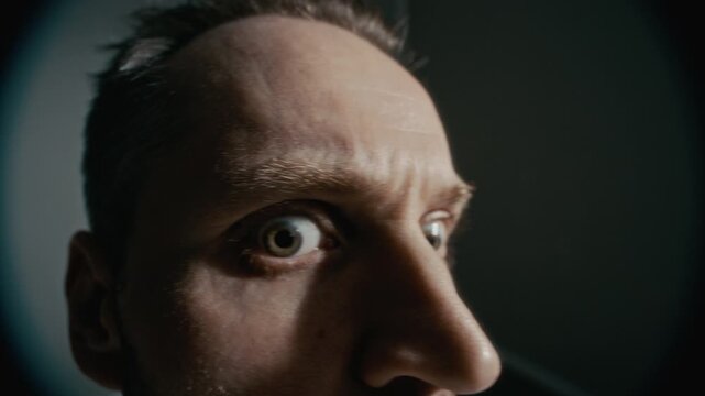 Closeup fisheye of middle aged Caucasian man staring wide eyed with fear and paranoia under flashing strobe light. Perfect for mental health awareness campaigns or psychiatric disorder documentaries