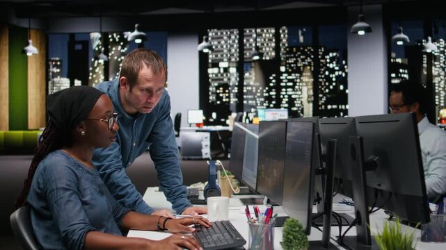 Manager supervising trainee typing code on computer, developing machine learning models to automate tasks in workspace. Team leader and intern writing programming language scripts on PC.
