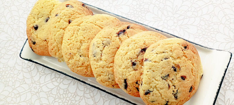 Chocolate chip cookies. Large pieces of fresh chocolate chip cookies served on a white rectangular plate.