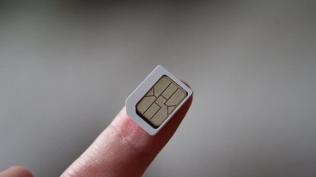 Close up of a sim card for a smart phone on finger
