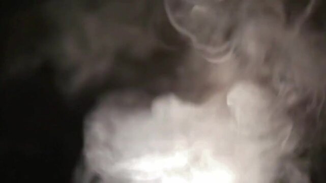 White smoke rising and swirling dynamically against a dark black background.
