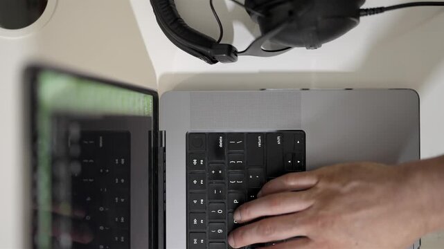 Workplace overhead view of hands typing on a laptop black keyboard