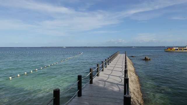 Wooden pier extending into calm tropical seawater near Vista Mar Beach Resort and Angasil Port, Mactan Island, Lapu Lapu City, Cebu, Philippines, static coastal composition with clear marine water.