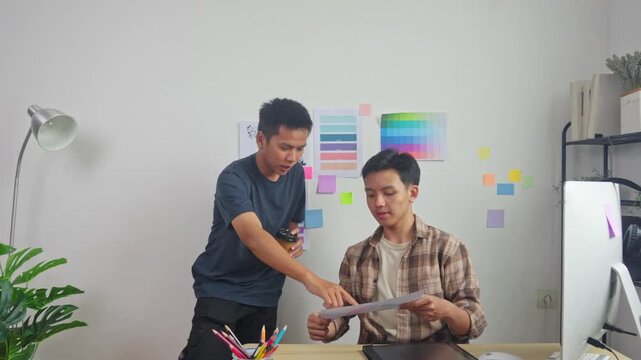 Two young creative designers collaborating and brainstorming on new project in modern office space