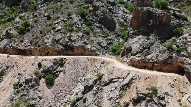 Drone shot following the path of the Karasu River with the legendary hand-carved Stone Road visible on the cliff with rock carved tunnel in Canyon in Kemaliye, Turkey.
