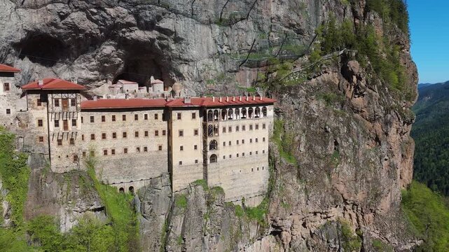 aerial view of the stone facade of Sumela Monastery on a sheer cliffside. Remarkable engineering, medieval orthodox architecture, and famous tourist attraction in Trabzon, Turkey.