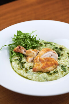 Chicken with green risotto on white plate