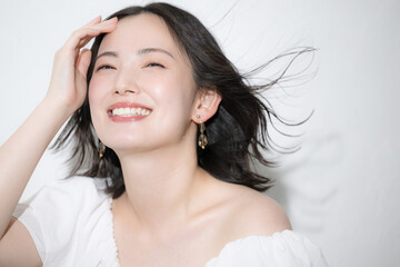 Fototapeta premium 風になびく髪と透明感のある笑顔が美しい若い女性のスキンケアやヘアケアビューティーイメージ