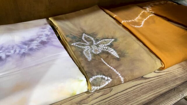 Collection of Colorful Folded Traditional Resist Dyed 
Fabric Displayed on Table in Indonesia Textile Shop