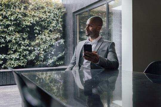 Man in a suit checking his smartphone in an office meeting room