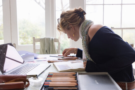 20 year old woman artist working on a drawing in her studio