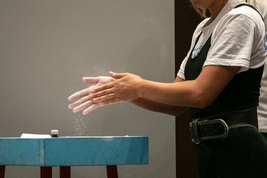 Female powerlifter applies talcum powder to her hands for tenacious grip