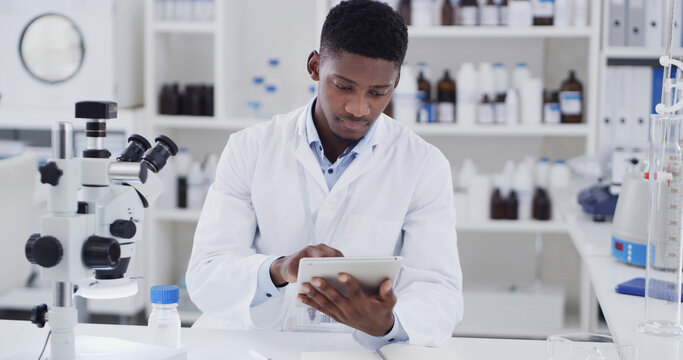 Scientist, lab or black man with tablet for medical research, discovery or test results. Male person, microbiologist or checking information with technology for science study, cure or clinical trial