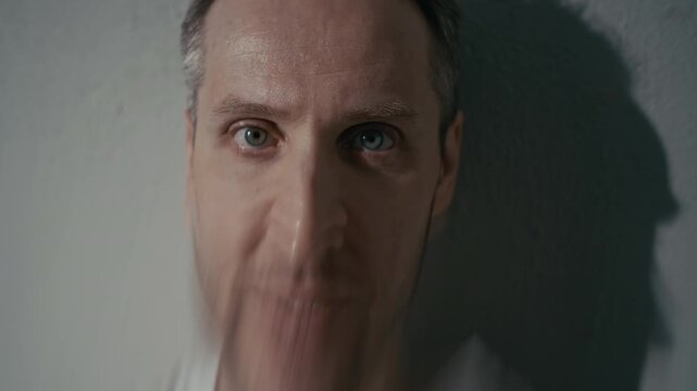 Closeup portrait of middle aged Caucasian man with distorted double vision effect smiling manically. Clip is suitable for mental health awareness campaigns or psychiatric clinic promotions
