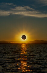 Total solar eclipse over a coastal lagoon at sunset with a spectacular reflection of the sun in the water in the Albufera of Valencia, Spain. © sirbouman