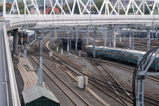 Layered railway tracks curve beneath a white bridge at Oslo station, where train platforms, glass structures and Norway infrastructure frame urban transit depth