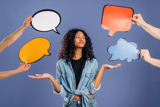 Young African American woman in denim jacket holds hands out with colorful speech bubbles around her against a solid purple background